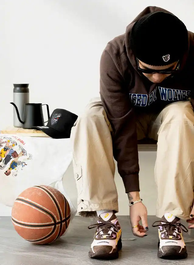 Basketball resting on the floor beside someone tying their sneakers.